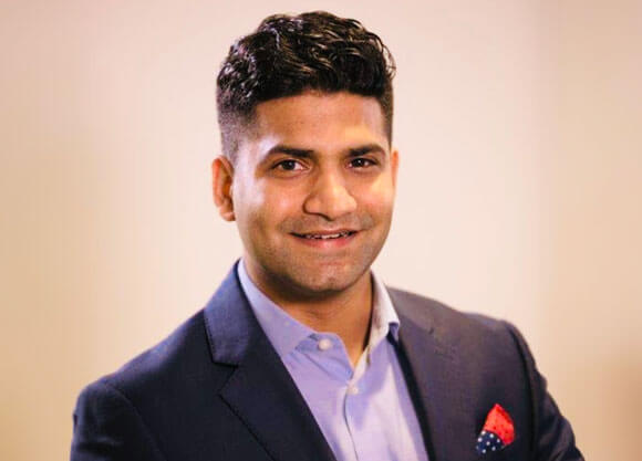 Akash Budhani smiles in a suit for a headshot.